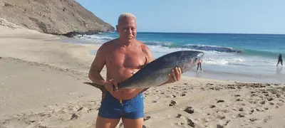 a man standing on the beach holding a fish at Mira Mar Mindelo in Mindelo