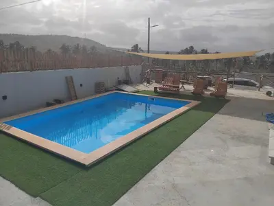 a large swimming pool with chairs and a fence at Quinta Achada Fazenda in São Tiago