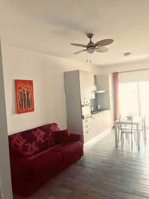 a living room with a red couch and a kitchen at Kite & Chill Sal Rei in Sal Rei