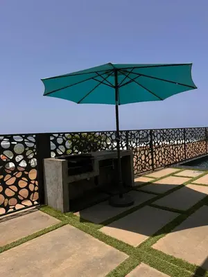 a green umbrella sitting next to a bench at CORAL BAY - Kode Villa in Cidade Velha