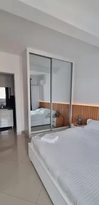 a bedroom with a large white bed and a mirror at Palmarejo Center Apartment Suites in Praia