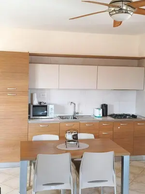 a kitchen with a wooden table and white chairs at HostySpot - Tropical Resort in Santa Maria
