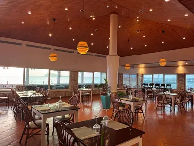 a restaurant with tables and chairs and windows at Murdeira V 17 J by RPG Group in Beirona