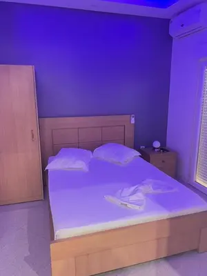 a purple bedroom with a bed with white sheets and pillows at Pensao Restaurante Recanto in Tarrafal