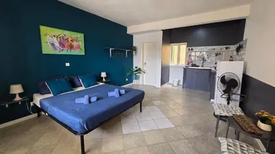 a blue bedroom with a bed and a kitchen at Celina's Cozy Studio & Beach Life in One in Santa Maria