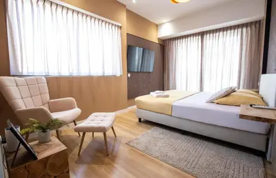 a bedroom with a bed and a chair and a television at Suncent apartment in Mindelo