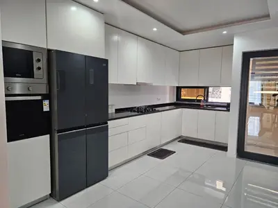 a kitchen with white cabinets and black appliances at T3 Duplex - Palmarejo Grande in Praia