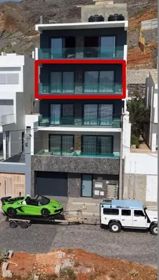 a green car and a van parked in front of a building at Boa Vista Apartment in Prainha
