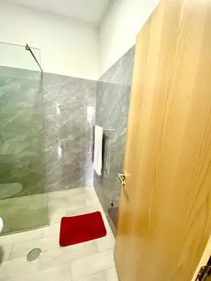 a bathroom with a shower with a red rug on the floor at APARTAMENTO 403 T2 Centro de Sal Rei, Boavista in Sal Rei