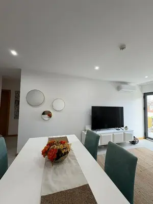 a white living room with a table and a television at Santa Maria Residence - Central T2 in Santa Maria