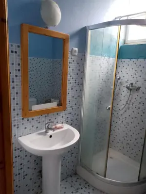 a bathroom with a sink and a shower with a mirror at Djabraba's Trail Triple SUITE in Vila Nova Sintra