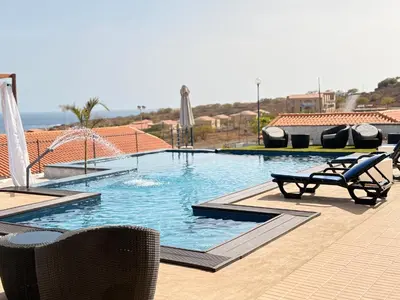 a large swimming pool with two chairs and avisor at Bougainvillea Villa in Cidade Velha