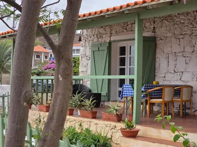 a patio with a green pergola and a table and chairs at Bougainvillea Villa in Cidade Velha