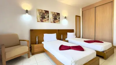 a hotel room with two beds and a chair at Exclusive 3-Bedroom Apartment Vila Verde Resort in Santa Maria