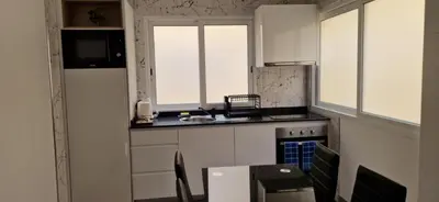 a kitchen with white cabinets and a table and a sink at Ines Studio T0 - Inforsal in Espargos