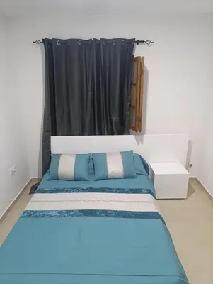 a bedroom with a blue bed with a black curtain at Sossego & Conforto in Espargos