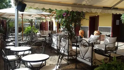 an outdoor restaurant with tables and chairs and umbrellas at The Colonial Guest House in São Filipe