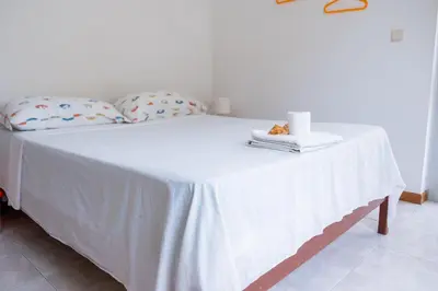 a white bed with a table with towels on it at Simabo's Backpackers' Hostel in Mindelo