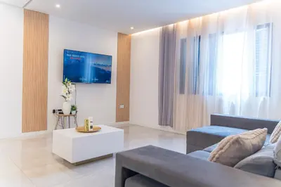 a living room with a couch and a tv on a wall at 3-bdr apt 10-min walk laginha beach - LCGR in Mindelo