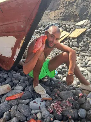 a man sitting on the rocks with a crab on his lap at Sinagoga Guesthouse in Ribeira Grande