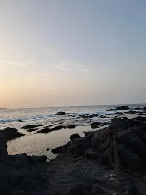 a beach with rocks and the ocean at sunset at Sinagoga Guesthouse in Ribeira Grande