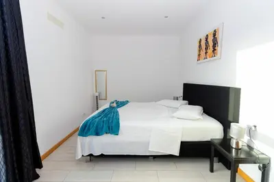 a bedroom with a white bed with a blue blanket on it at 1 Bedroom - 150m from the Beach - Pool in Santa Maria