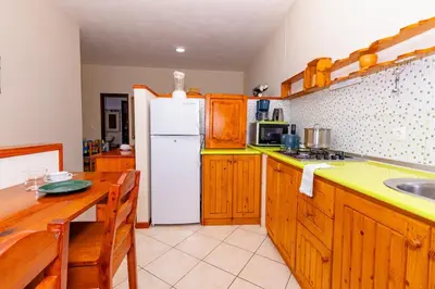 a kitchen with wooden cabinets and a white refrigerator at T1 - 800m from the beach - located in the city center in Santa Maria