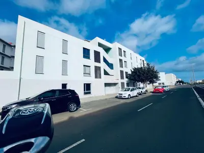 a white building with cars parked on the side of a street at APPARTEMENT IDEAL POUR ESCALE a PRAIA in Praia