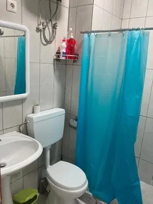 a bathroom with a toilet and a blue shower curtain at Prédio IFH Maio in Vila do Maio