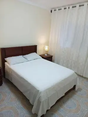 a bedroom with a large white bed with a lamp at Casatata in São Filipe