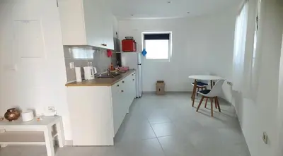 a white kitchen with a sink and a table at Studio Alto Saco in Tarrafal
