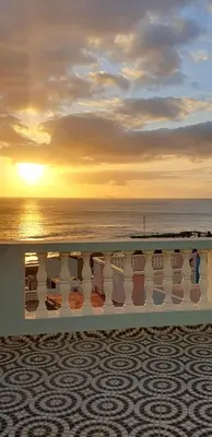 a view of the ocean at sunset from a balcony at Residência Alto Saco, Double room with private bathroom in Tarrafal