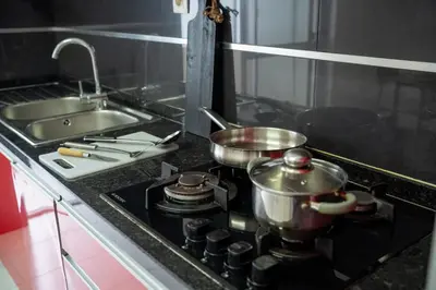 a kitchen with a stove with two pots and a sink at T2 com escritório - Férias Teletrabalho in Praia