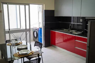 a kitchen with red cabinets and a table with chairs at T2 com escritório - Férias Teletrabalho in Praia