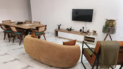 a living room with a table and chairs and a tv at Apartamento Cidade in Mindelo