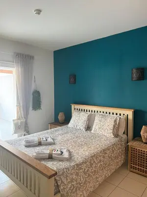 a bedroom with a large bed with a blue wall at Vila Verde Lantana B103 by RPG Group in Santa Maria