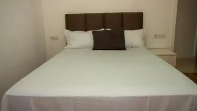 a large white bed with a brown headboard in a room at Domus Lima in Mindelo