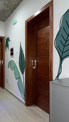 a room with a wooden door with leaves painted on the wall at The Pink Banana in Paul