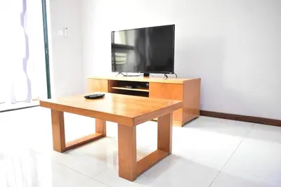 a living room with a wooden table and a television at Cozy Palm in Praia