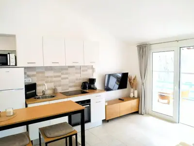 a kitchen with white cabinets and a table and a television at Lamore 01 - more comfortable of all in Beirona