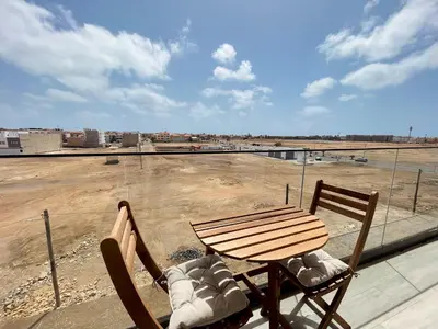a table and chairs on a balcony with a view of a field at Apartamento T0 - MedSal Residence in Prainha