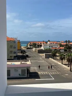 two people walking down a street with the ocean at APARTAMENTOS COSTA MCC - New apartments near city center & beach in Santa Maria