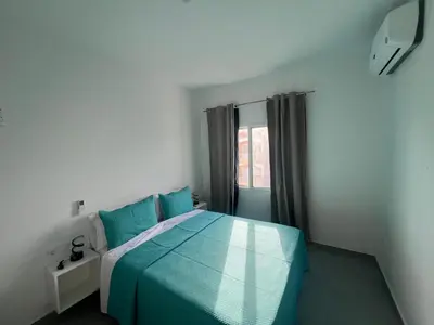 a bedroom with a blue bed and a window at APARTAMENTOS COSTA MCC - New apartments near city center & beach in Santa Maria