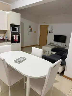 a kitchen and living room with a white table and chairs at vitoria in Praia