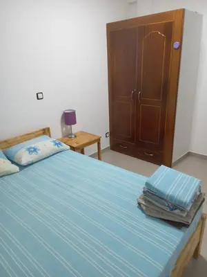a bedroom with a bed with blue sheets and a wooden cabinet at T3 Mindelo in Mindelo