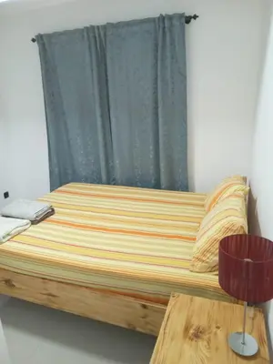 a bed in a room with a window and a table at T3 Mindelo in Mindelo