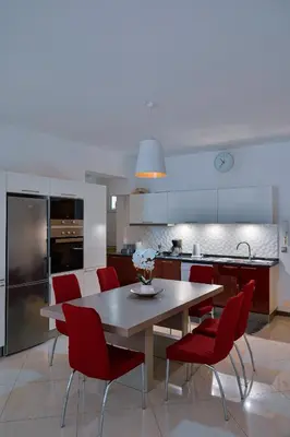 a kitchen with a wooden table and red chairs at Tabanka Azul - 2 BdR Cozy and Comfort Apt Near UN in Praia