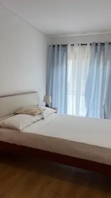 a bedroom with a large bed with blue curtains at Elson Apartment - T1 - Cidadela - Security, Comfort in Praia