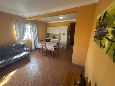 a kitchen and a living room with a table and a couch at Holiday Properties Tropicana in Santa Maria