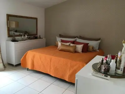 a bedroom with a bed with an orange blanket and a mirror at Duplex Avenida Ilhéu Santa Maria, Palmarejo in Praia